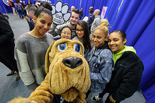 John Jay Bloodhound taking a selfie with students at John Jay Homecoming
