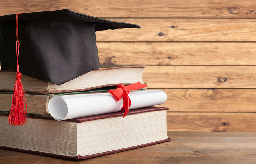 Graduation cap and diploma sitting on books