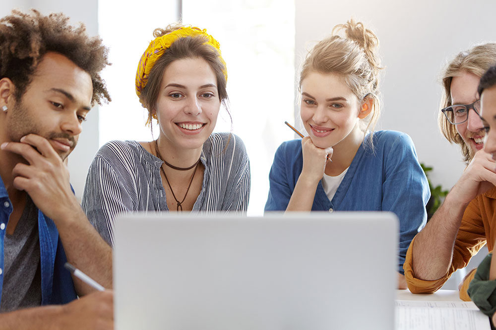 group of students looking at a laptop