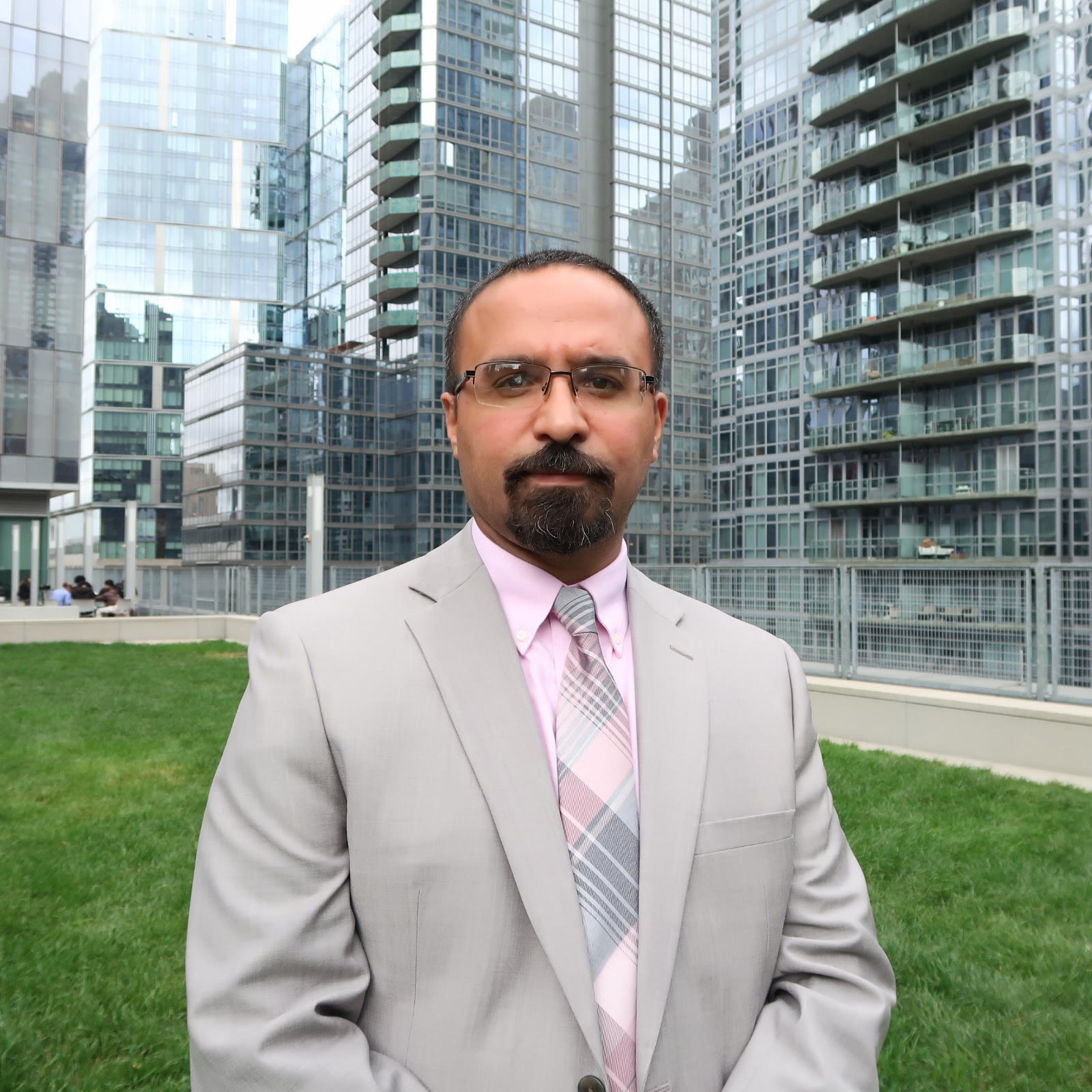 Professor Jason D. Rivera wearing a gray suit and pink shirt on the John Jay College Jaywalk