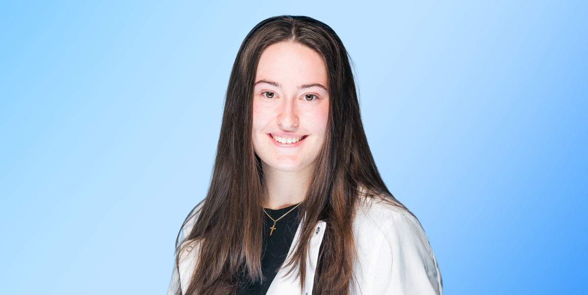 Brooke Fontaine is wearing her PRISM lab coat, her hair is down, and she is facing the camera smiling.