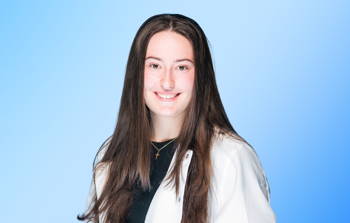 Brooke Fontaine is wearing her PRISM lab coat, her hair is down, and she is facing the camera smiling.