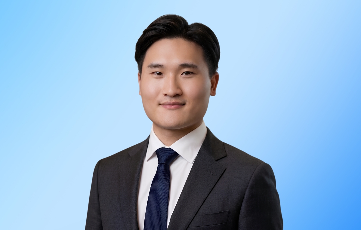 Haoran He '26 smiles at the camera. He is wearing a dark suite, white buttoned-shirt and navy blue tie.