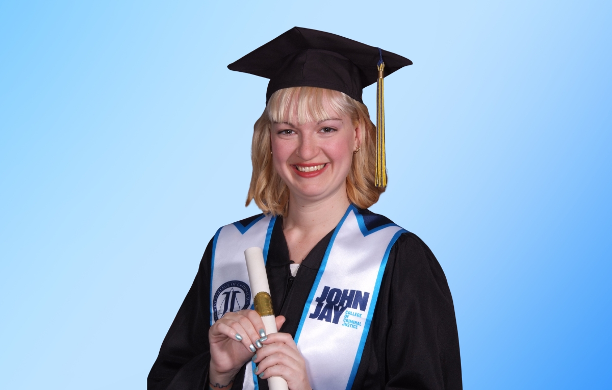 Mya Levis smiles at the camera while wearing her graduation cap and gown, and John Jay College stole.