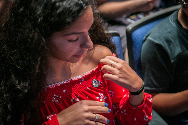 A new student puts on her John Jay pin 