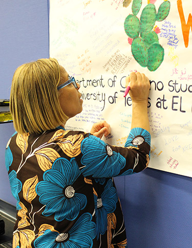 President Mason signing the El Paso Strong poster created by John Jay students and presented to Montelongo in support of UTEP