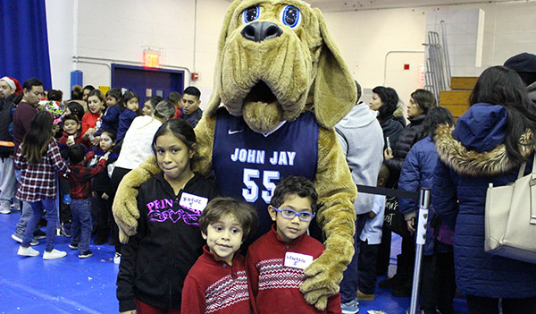 Bloodhound posing with kids at the John Jay Annual Children's Holiday Party