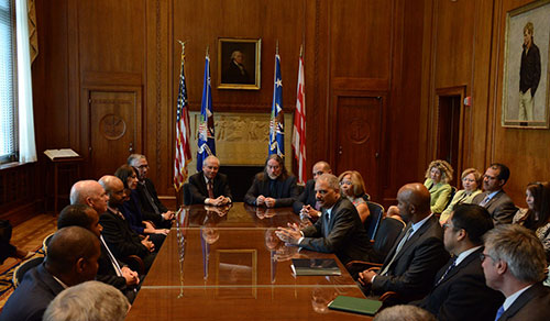 Attorney General Eric Holder speaking to a group of people around a table