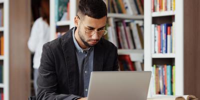 student with laptop in library