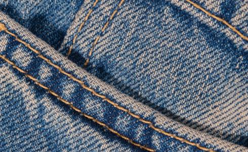 Close-up of blue denim jeans showing a front pocket with visible stitching and seam details