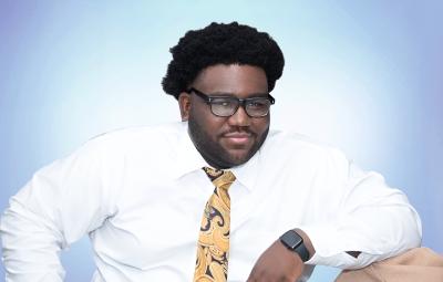 Alumnus Alain Delphonse '25 sits facing the camera.