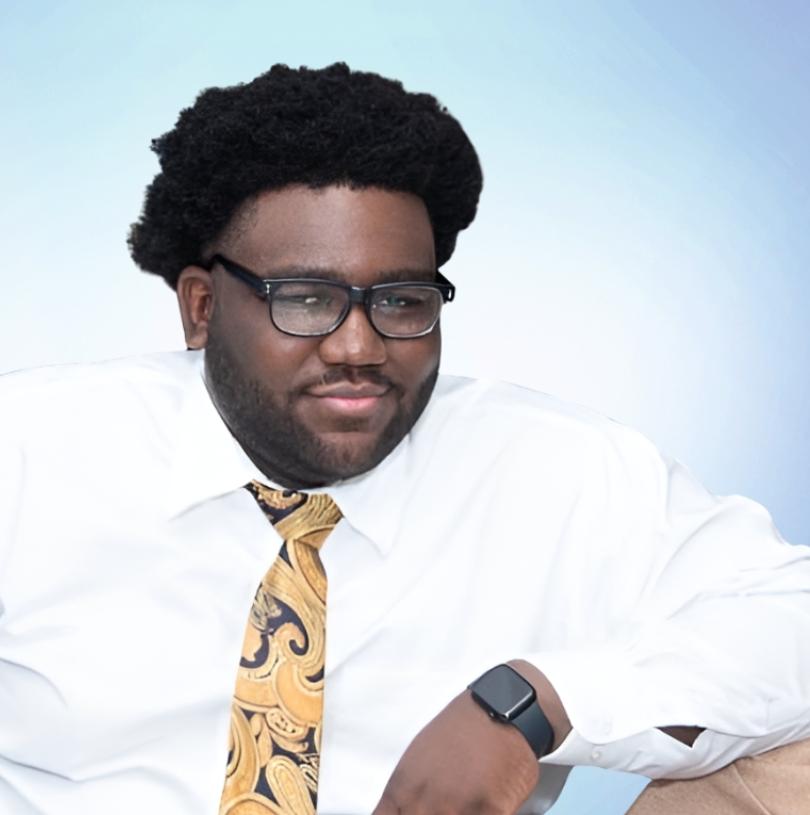 Alumnus Alain Delphonse '25 sits facing the camera.